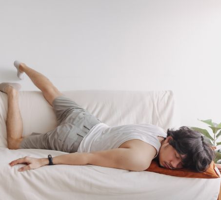 young man sprawled across sofa bed - lack of sleep