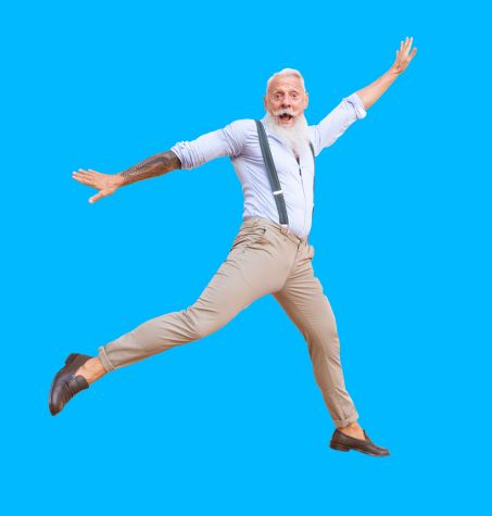 Senior hipster with tattoos leaping in the air against a blue background