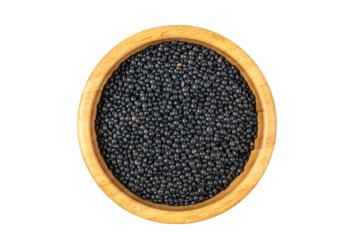 a bowl of black lentils in a wooden bowl against a white background