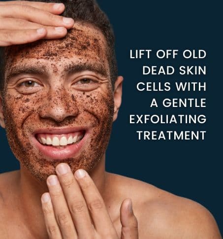 smiling man exfoliating his facial skin with a mud exfoliation treatment