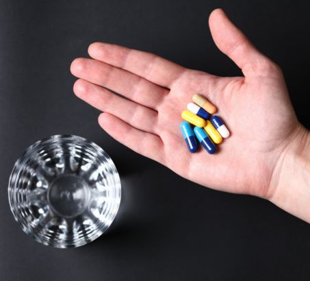 Handful of colourful high strength pills and a glass of water