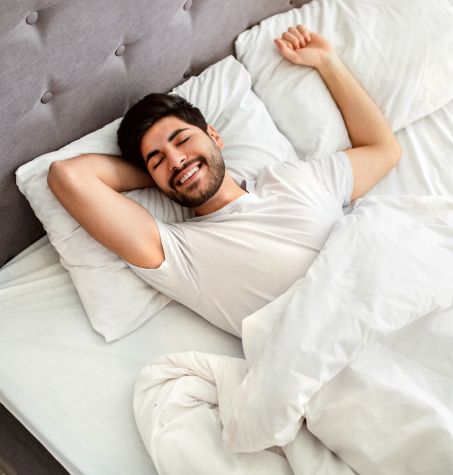 Happy, satisfied guy stretching out on the bed after a break up