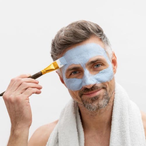man applying face mask to his face