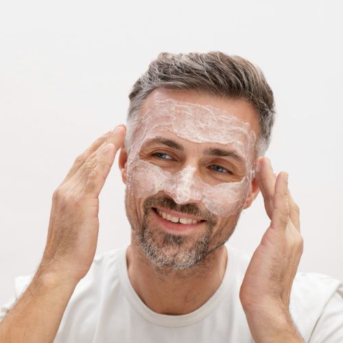 mature man exfoliating his face with cream face scrub