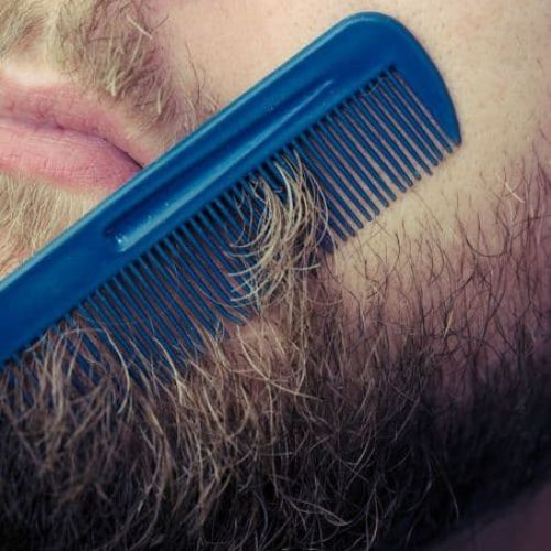 close up of a man combing out flakes from beard