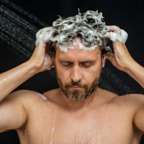 man focused on massaging scalp while washing hair with his eyes closed