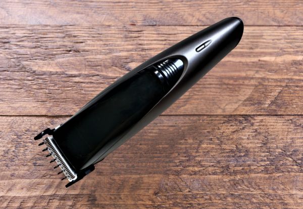 sleek black beard trimmer against a plain brown wood background