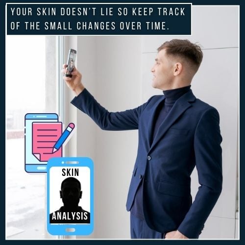A man stands near a window in soft natural light, taking a photo of his face with his phone to track skin changes. A skincare journal or app is visible nearby, showing he's monitoring progress over time.