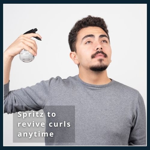 Close-up of curly hair being refreshed with a fine mist from a travel spray bottle, illustrating how a light spritz revives curls throughout the day.