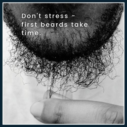 Close up of a man with a patchy beard, he is gently tugging at a few beard hairs symbolizing that early beard growth is normal and takes time