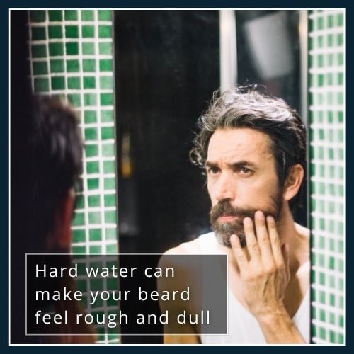 Man looking at his beard in the mirror after hard water exposure showing dryness