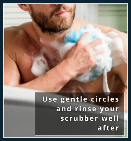 Man using loofah in shower with visible soap suds and relaxed expression