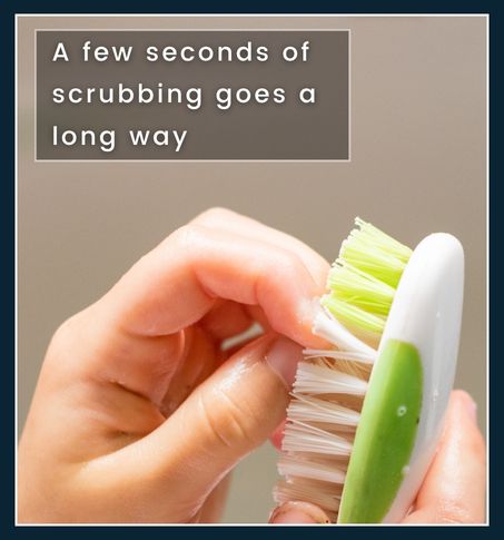 Man using nail brush under running water to clean fingernails