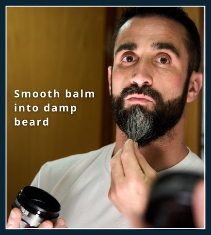 Man smoothing beard balm into a damp beard with his fingertips