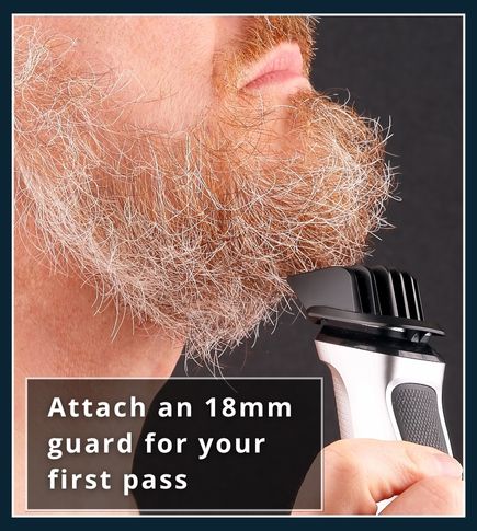 Man holding an electric beard trimmer with an 18 mm guard attached next to his beard