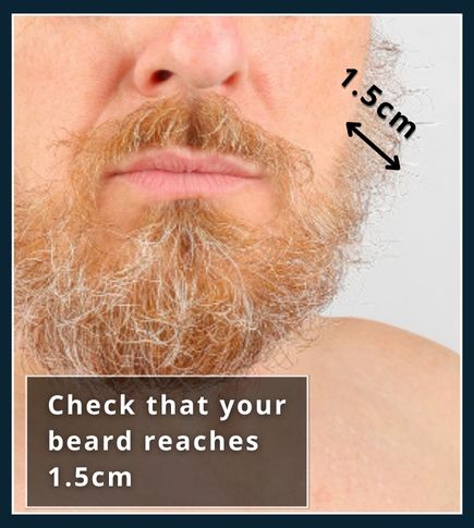 Close‑up of a metal ruler held against beard stubble showing a 1.5 cm length
