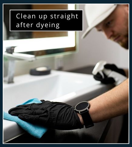 man wearing gloves, using a cloth and spray cleaner to clean up the bathroom