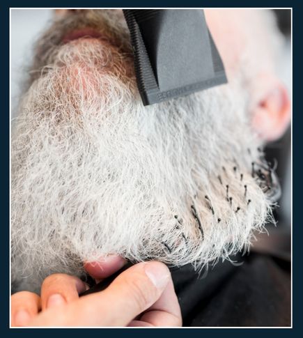 Man using a hair dryer on beard with heat protectant spray