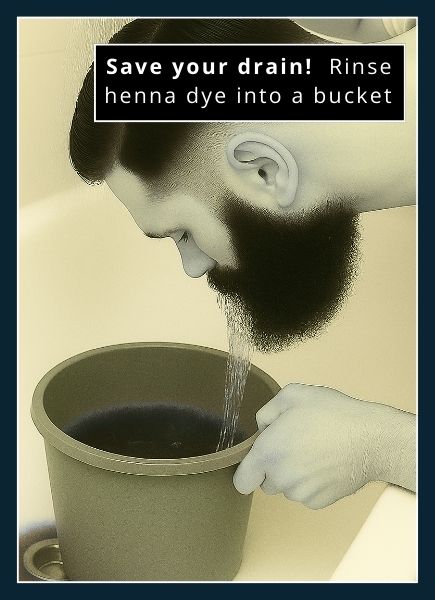 man rinsing natural henna beard dye off his beard into a bucket in the tub. He is using a handheld shower to direct the water at his beard