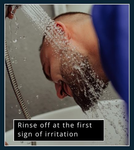 Man rinsing beard dye off at sink after irritation