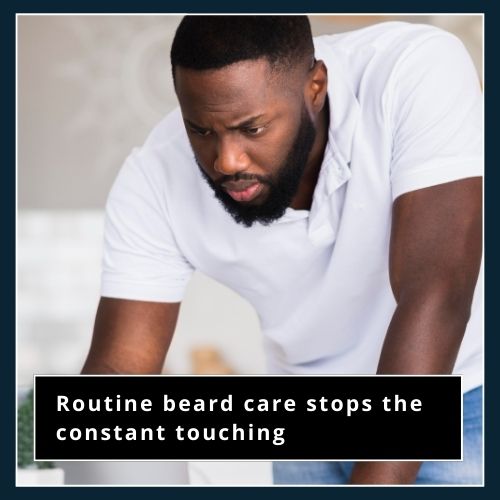 a man relaxed and focused at his work desk. His morning beard care routine has helped him to avoid messing up his beard by touching it later in the day