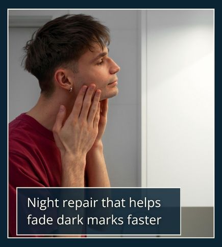 Dimly lit close-up of a man’s face in mirror reflection with warm side lighting, symbolising night-time retinoid use for fading dark marks.