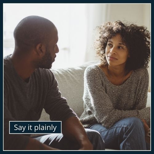 A man and woman sitting on a sofa during a quiet conversation. The man looks open and steady, while the woman looks hesitant as she listens.