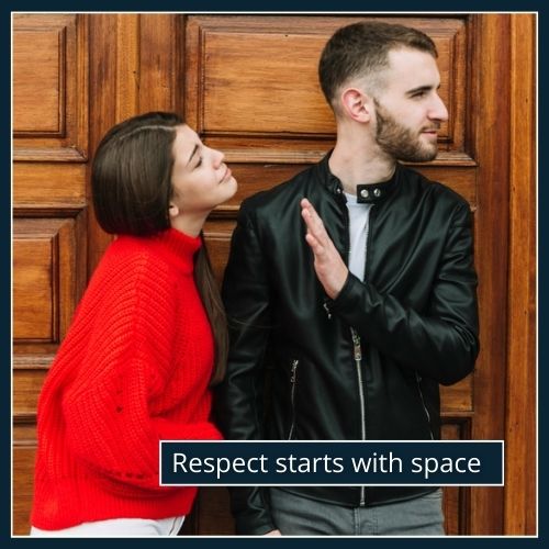 A man steps back slightly with his hand raised as a woman leans in to talk, showing a clear moment of ignored personal space.