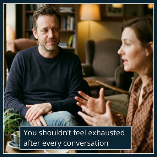 A man listens quietly while a woman talks, his expression calm but weary, reflecting emotional fatigue from constant negativity.