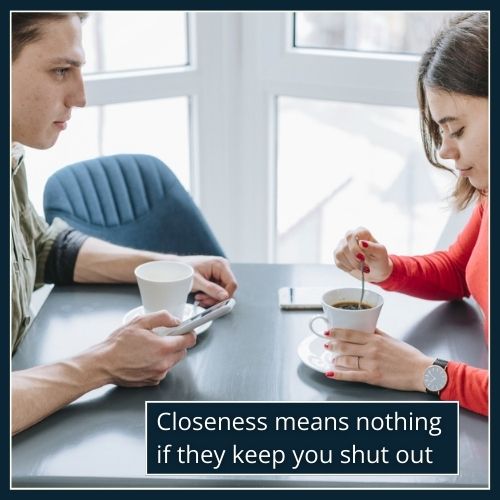 A man and woman sit close together but disconnected, her attention elsewhere while he looks on quietly, symbolising emotional unavailability.