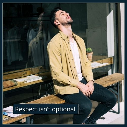 A man sits alone at a café table, leaning back slightly with an empty chair opposite him, symbolising emotional distance and lack of respect in a relationship.