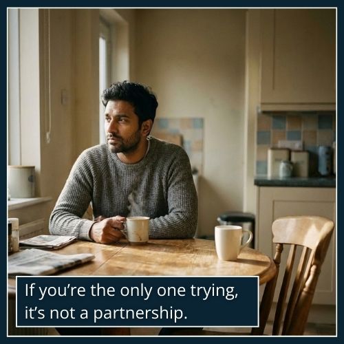 A man sits alone at a table with two coffee mugs, one untouched, symbolising the imbalance caused by emotional unavailability.