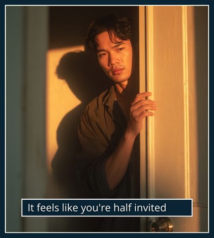 Man standing at a half-open doorway with light on one side and shadow on the other, showing emotional uncertainty.