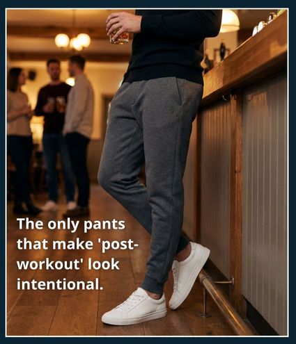 Man standing at a bar wearing slim tapered joggers in a neutral colour that hold their shape and look suitable for both gym and casual wear