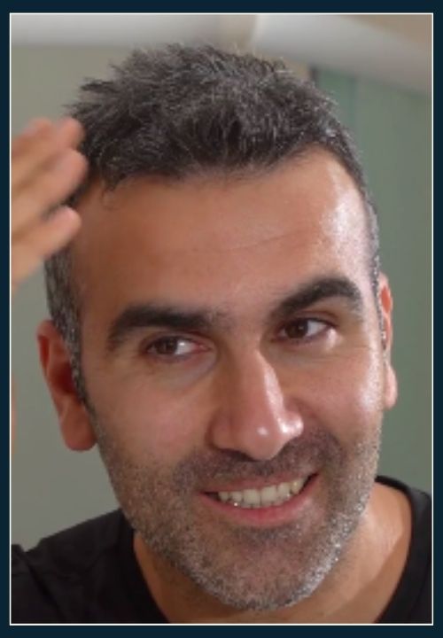 man styling his textured fringe in the mirror