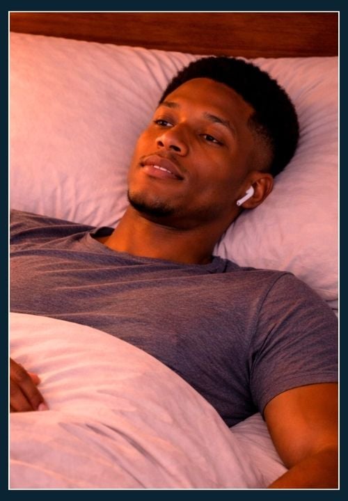 a man lying in his bed with headphones on listening to audio hypnotherapy for better anxiety management.