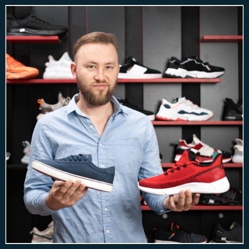 man holding two different pairs of trainers and trying to make a decision which one is best for his personal needs.