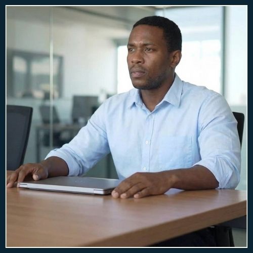 A man sitting confidently at his work station as if getting ready to share the decision that he has already made.