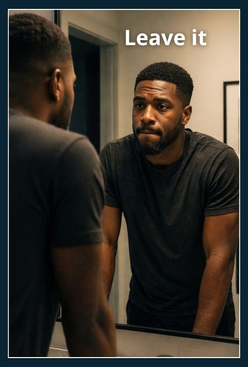 man looking at himself in mirror appearing thoughtful and holding back reaction