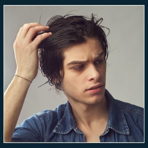Man with hair that is heavily laid down by product. The hair style has lost shape and he is trying to create volume in the front of his hair style.