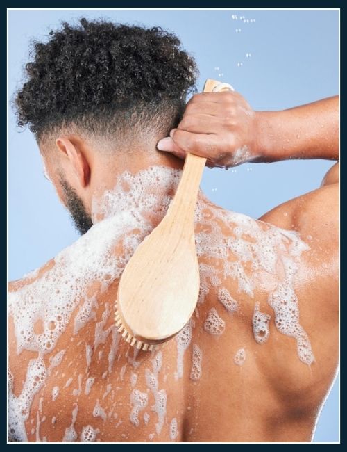 Man using a long-handled shower brush to wash the middle of his back.
