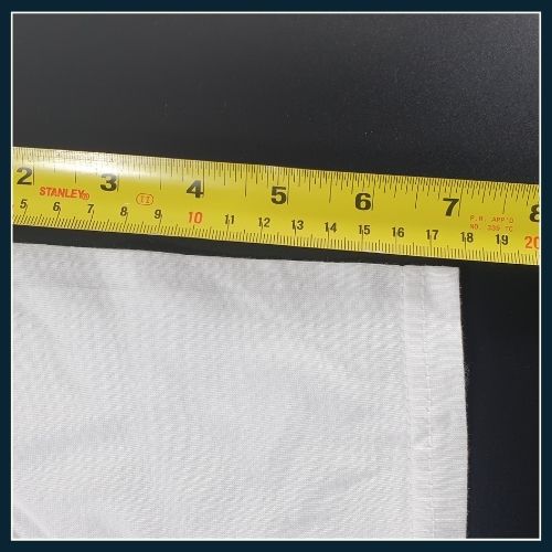 measuring tape held against sleeve of white T-shirt.